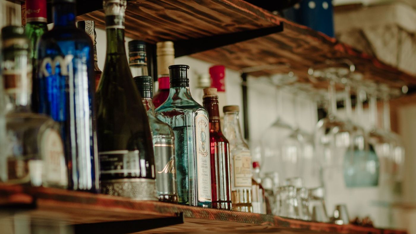 Bottles of spirits and glassware on a wooden bar shelf